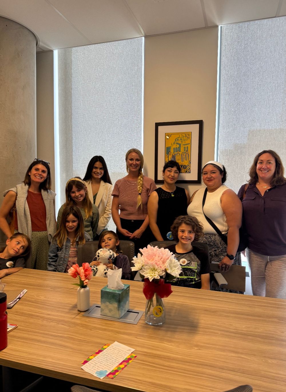 Advocates and children pose together behind a conference table in an office.