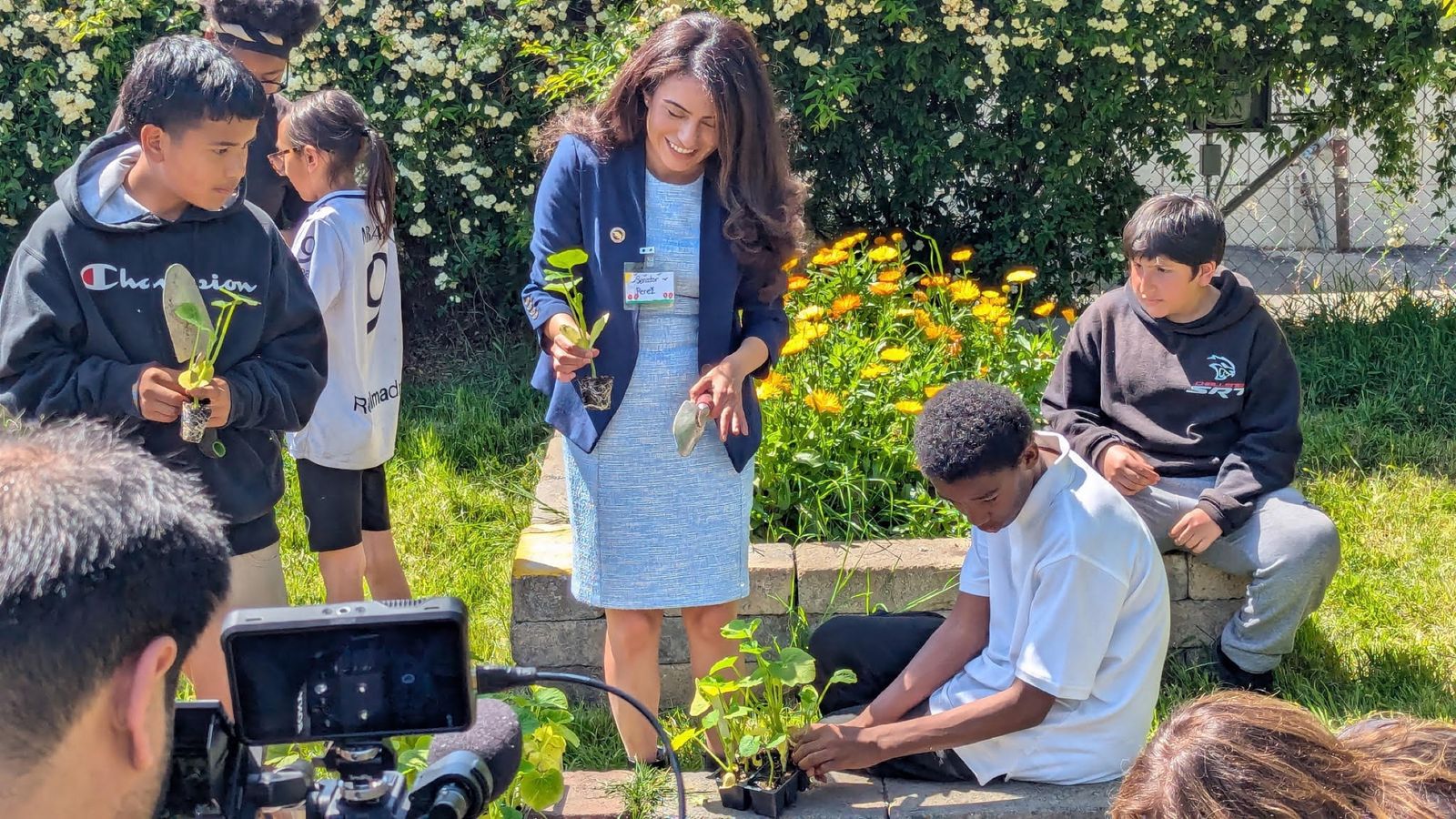 Students planting seedlings in a school garden with an adult